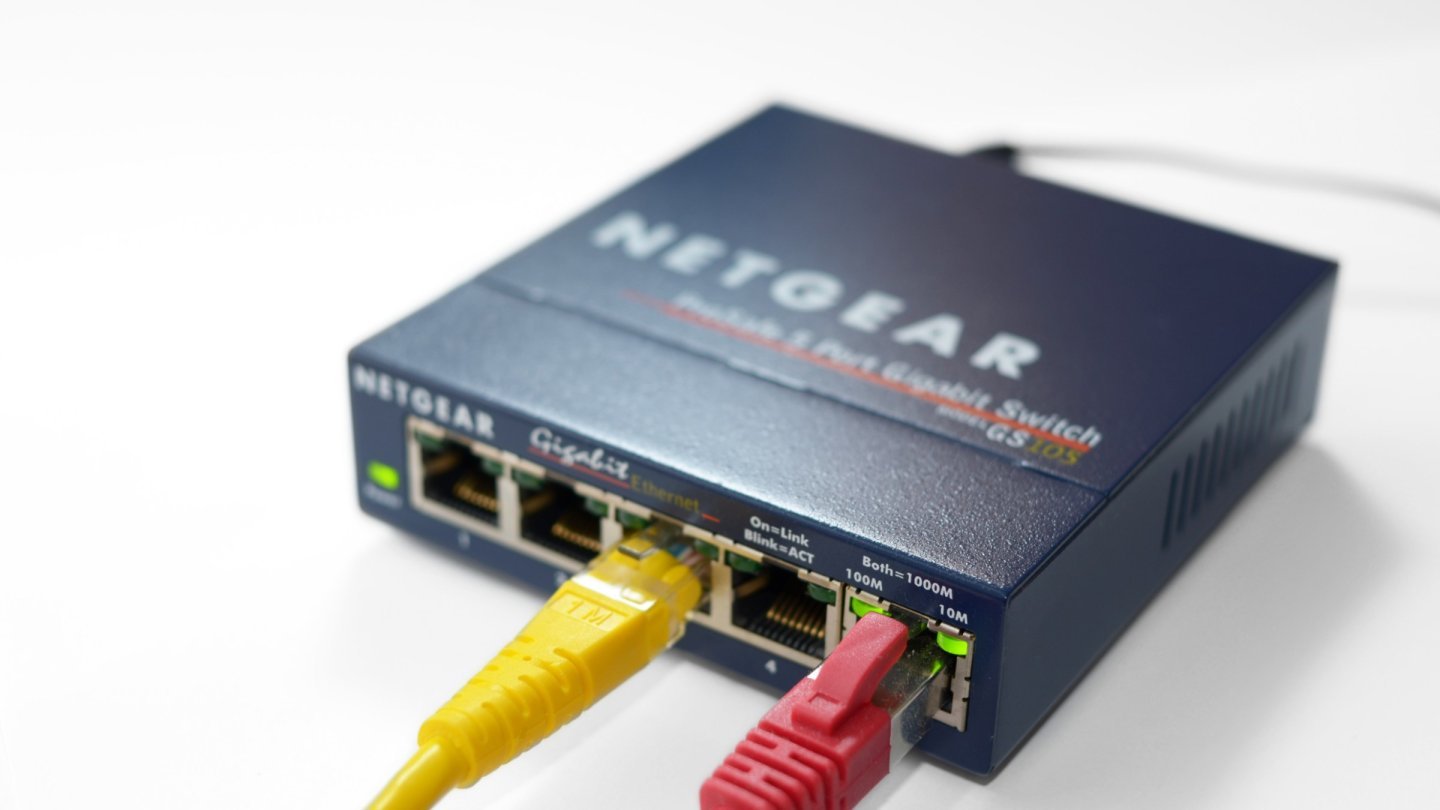 cablu Ethernet Switch de rețea gigabit cu cinci porturi, cu un cablu Ethernet galben și unul roșu conectate