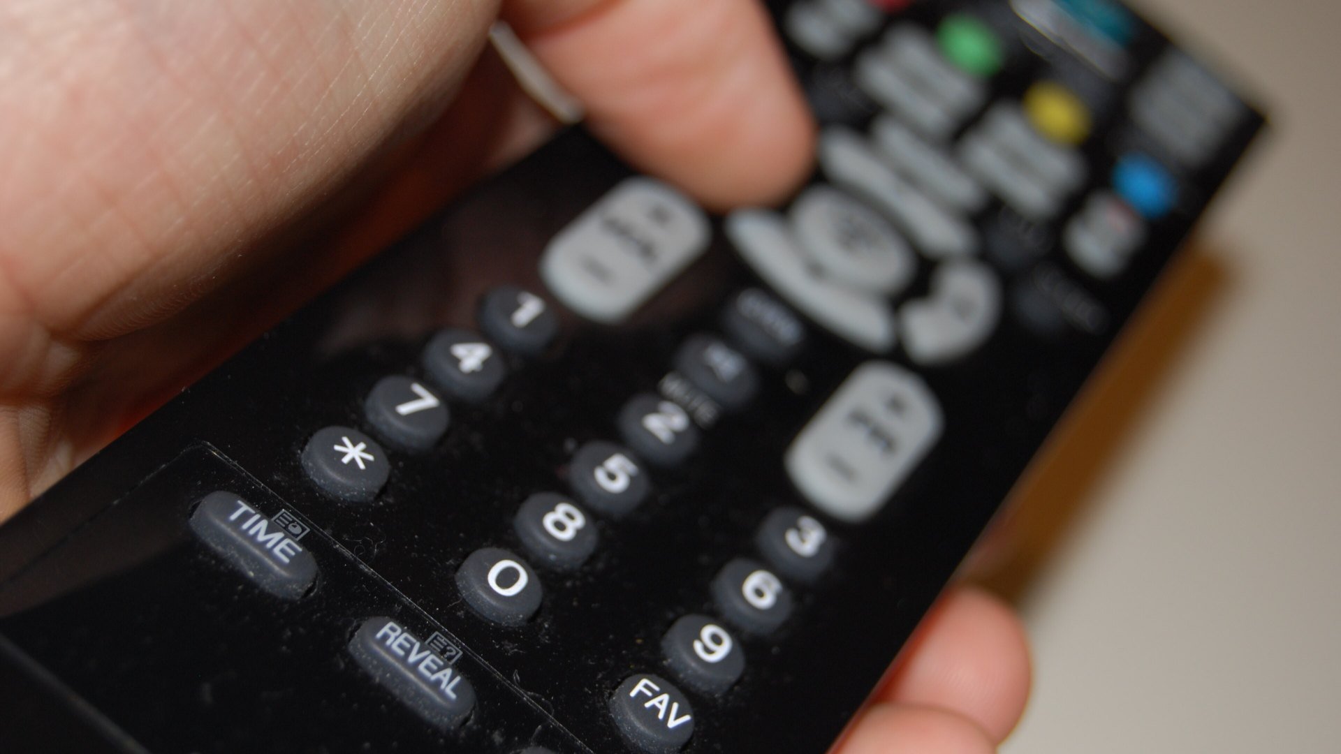 Mână care ține o telecomandă de televizor, pentru alegerea canalelor din FILMBOX+ Stream